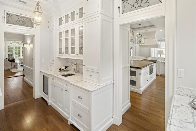 bar with dark wood-style floors, pendant lighting, a sink, and backsplash