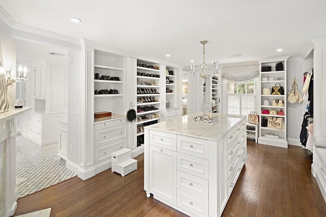 walk in closet with dark wood-style flooring and an inviting chandelier