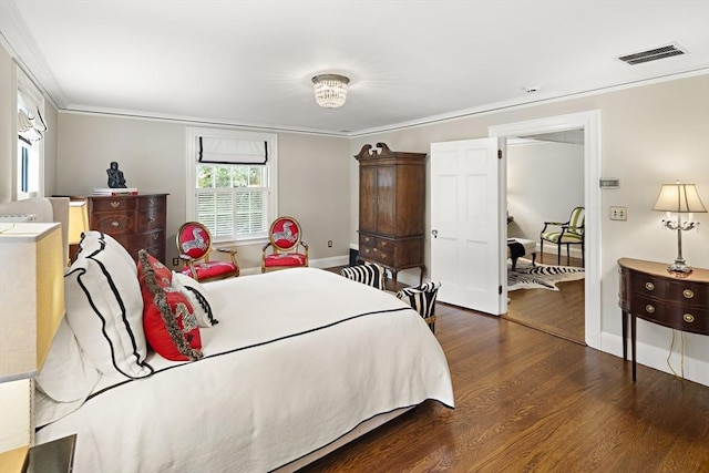 bedroom with baseboards, wood finished floors, visible vents, and crown molding