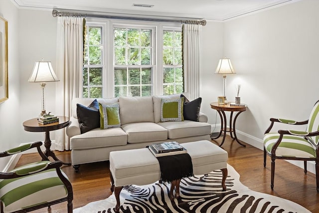 living area with visible vents, crown molding, baseboards, and wood finished floors