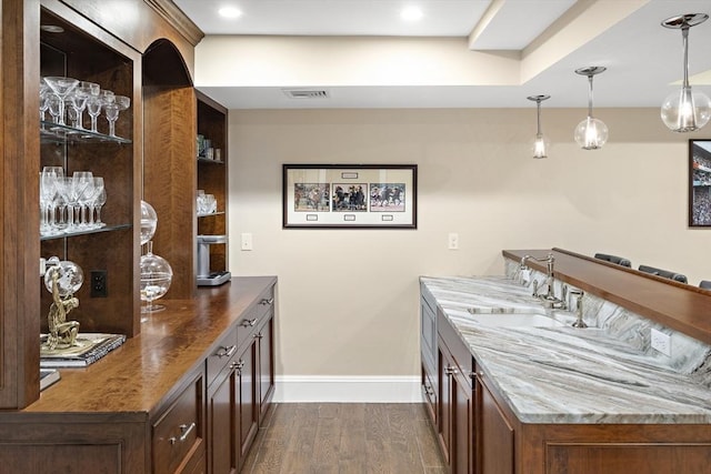 bar with visible vents, dark wood finished floors, hanging light fixtures, and baseboards