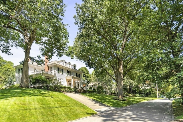 view of front of house featuring a balcony and a front lawn