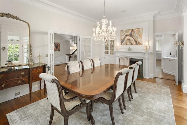 dining area with a wainscoted wall, light wood finished floors, and crown molding