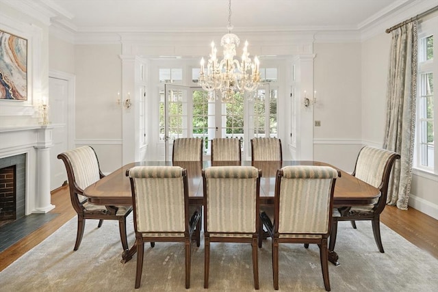 dining area with a fireplace with flush hearth, a chandelier, ornamental molding, and wood finished floors