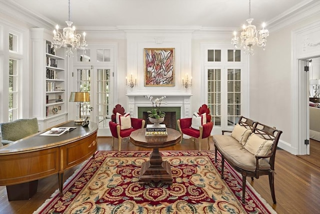 living area with built in shelves, dark wood-style flooring, an inviting chandelier, crown molding, and a fireplace