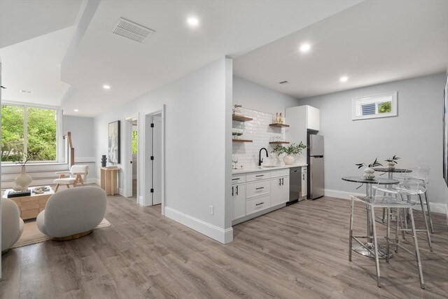 67 Pine St Unit 2, Dedham, MA 02026 - kitchen with stainless steel appliances, open shelves, light countertops, white cabinets, and tasteful backsplash