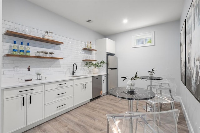 67 Pine St Unit 2, Dedham, MA 02026 - kitchen featuring appliances with stainless steel finishes, open shelves, a sink, light wood-type flooring, and decorative backsplash