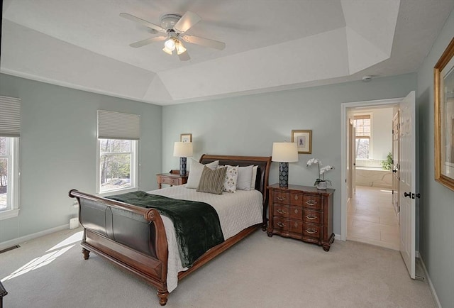 bedroom featuring a ceiling fan, a tray ceiling, light colored carpet, and baseboards