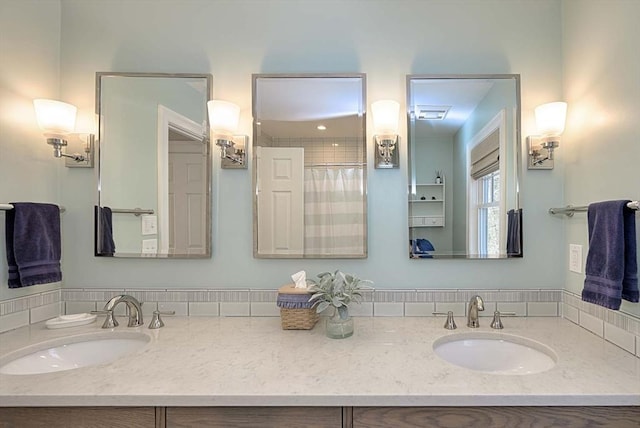 bathroom with curtained shower, double vanity, and a sink