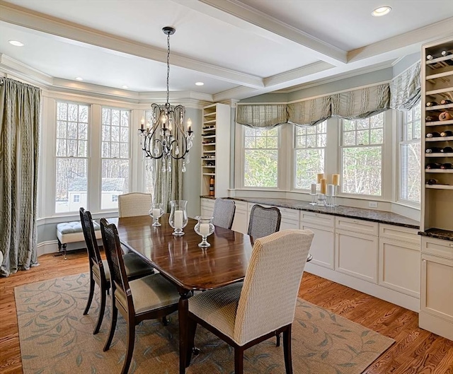 dining area with light wood-type flooring, beam ceiling, a notable chandelier, and ornamental molding