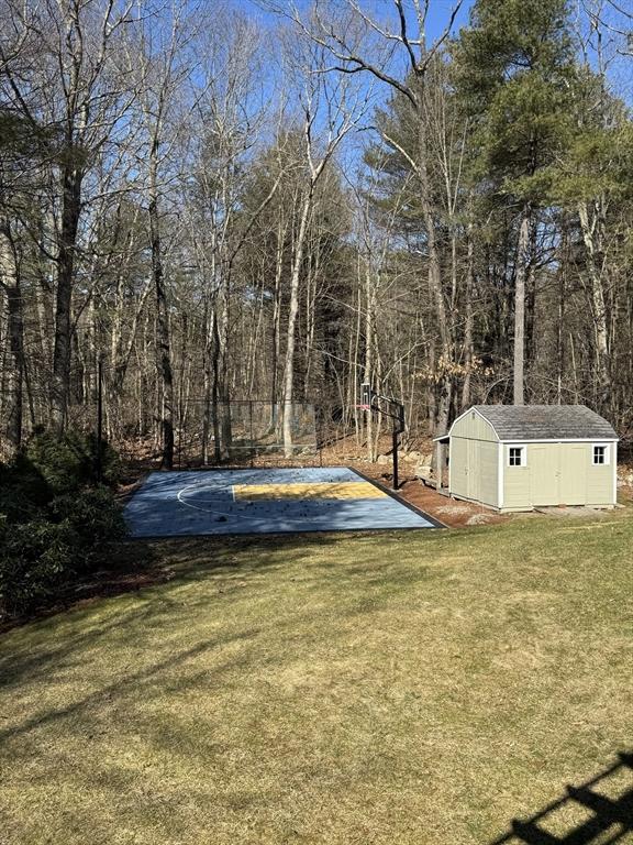 view of yard featuring an outbuilding and basketball hoop