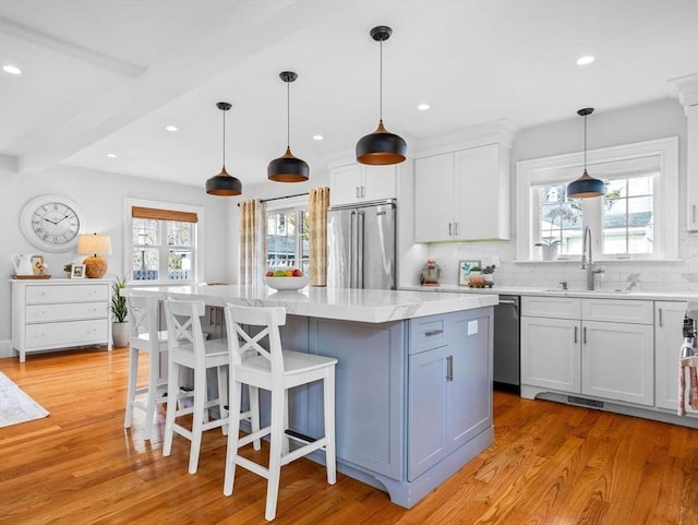 kitchen with a sink, light wood finished floors, high end fridge, and a center island