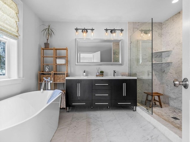 full bath featuring double vanity, a marble finish shower, marble finish floor, a freestanding tub, and a sink