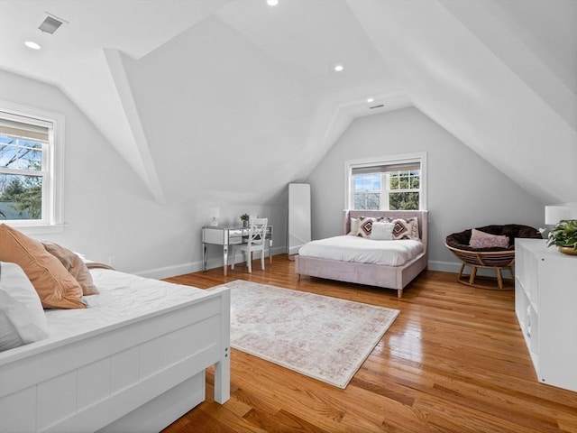 bedroom with baseboards, visible vents, vaulted ceiling, and wood finished floors