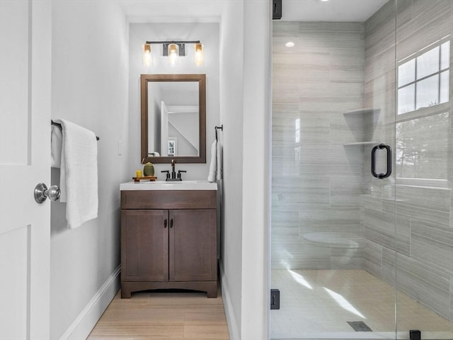 full bathroom with a shower stall, baseboards, and vanity