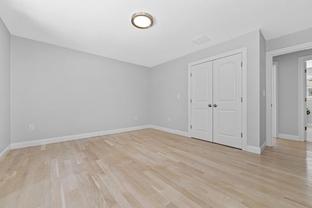 unfurnished bedroom with light wood-type flooring and a closet