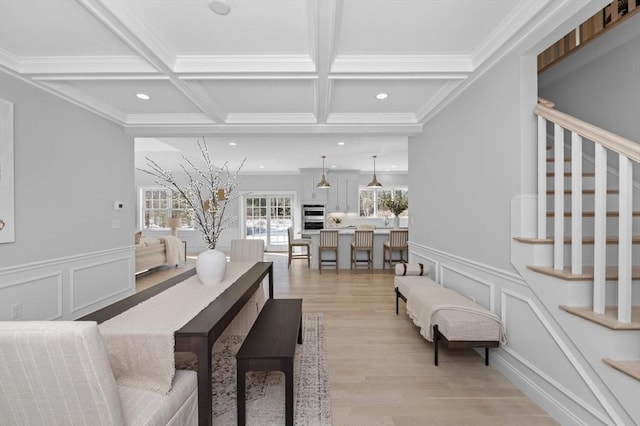 living room with beamed ceiling, ornamental molding, coffered ceiling, and light hardwood / wood-style flooring