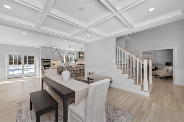 dining space featuring beamed ceiling, ornamental molding, coffered ceiling, and light wood-type flooring