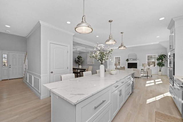 kitchen with white cabinetry, decorative light fixtures, light hardwood / wood-style flooring, and a center island