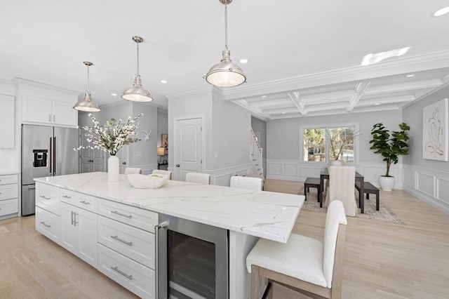 kitchen with stainless steel built in refrigerator, wine cooler, white cabinets, a kitchen bar, and decorative light fixtures