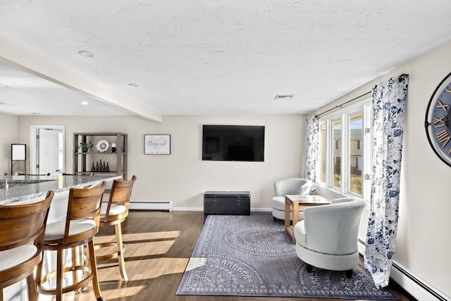 living area with dark wood finished floors, a textured ceiling, baseboards, and a baseboard radiator