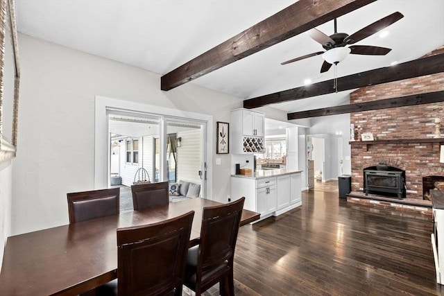 dining space with a ceiling fan, dark wood-style flooring, lofted ceiling with beams, a dry bar, and a wood stove