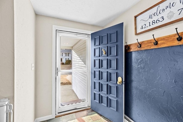 doorway to outside with baseboards and a textured wall