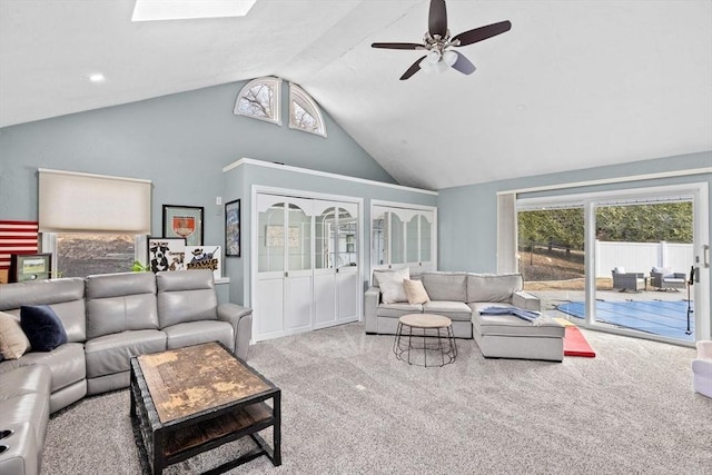 carpeted living area with high vaulted ceiling, a healthy amount of sunlight, a skylight, and a ceiling fan