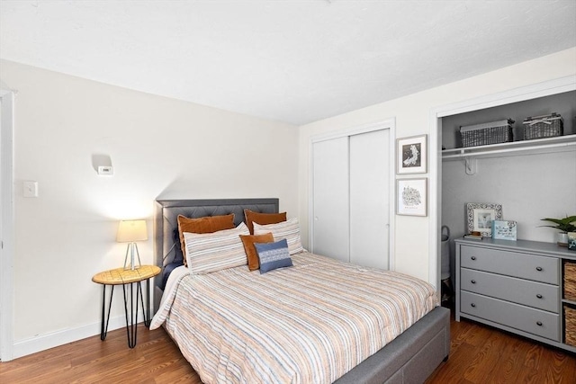 bedroom featuring wood finished floors, baseboards, and two closets