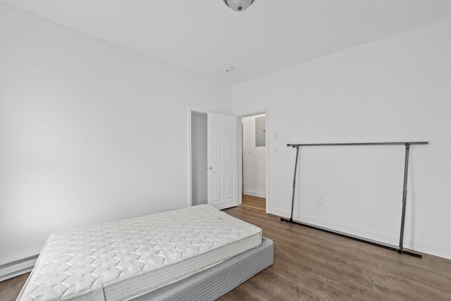 bedroom with dark wood-type flooring and a baseboard heating unit