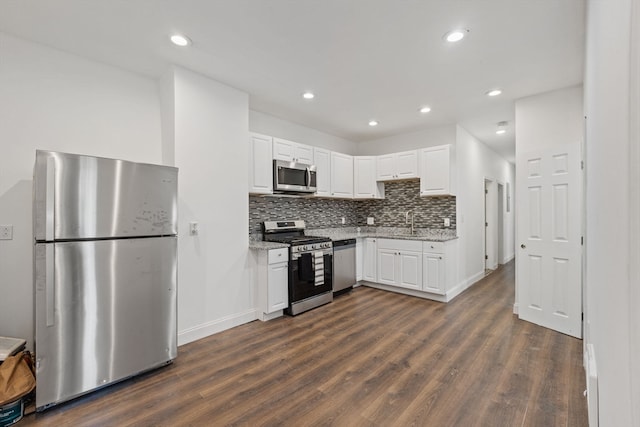 kitchen featuring light stone countertops, dark hardwood / wood-style flooring, appliances with stainless steel finishes, tasteful backsplash, and white cabinetry