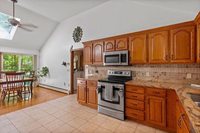 344 Mayfair Rd, Dennis, MA 02660 - kitchen with appliances with stainless steel finishes, a baseboard heating unit, a skylight, brown cabinets, and decorative backsplash