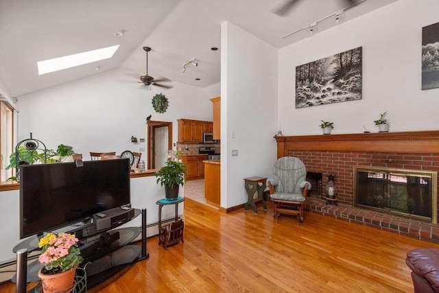 344 Mayfair Rd, Dennis, MA 02660 - living room featuring rail lighting, a skylight, a fireplace, light wood-style floors, and ceiling fan