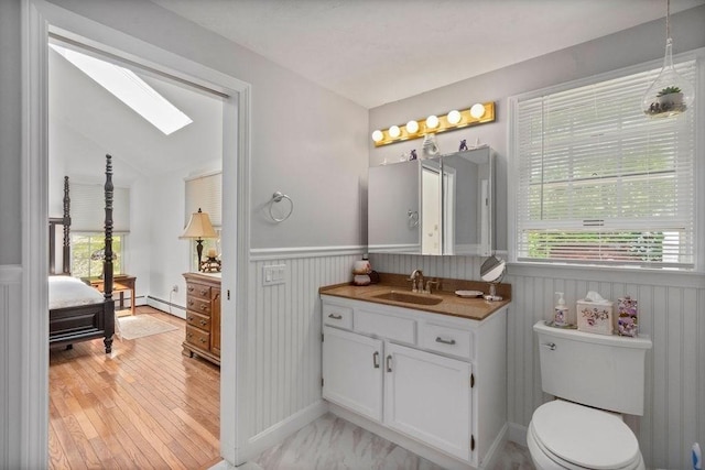 344 Mayfair Rd, Dennis, MA 02660 - bathroom featuring a skylight, vanity, a wainscoted wall, a baseboard radiator, and wood finished floors