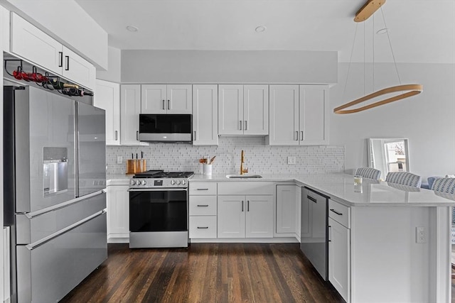 kitchen featuring stainless steel appliances, a peninsula, a sink, white cabinets, and light countertops