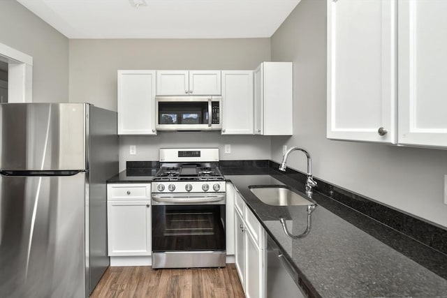 kitchen featuring white cabinetry, sink, dark stone counters, and appliances with stainless steel finishes