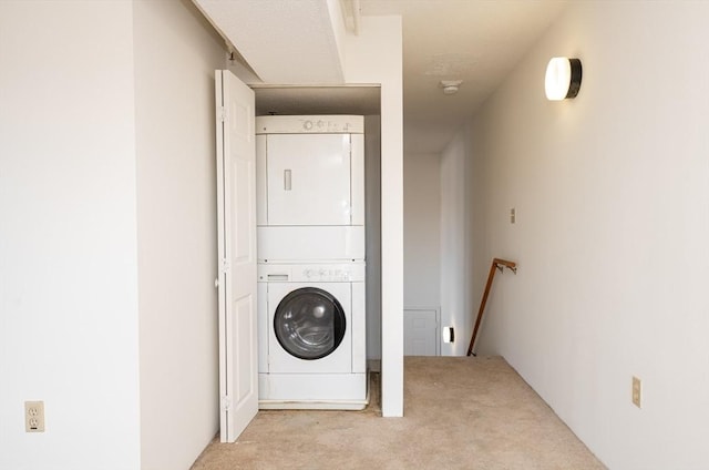 clothes washing area with light colored carpet and stacked washer / dryer