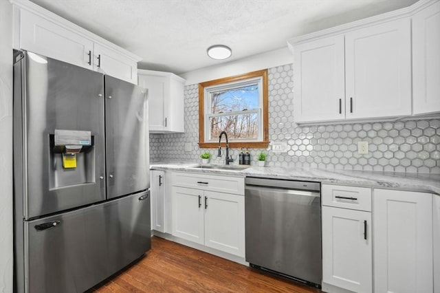 kitchen with tasteful backsplash, white cabinets, dark wood-type flooring, stainless steel appliances, and a sink