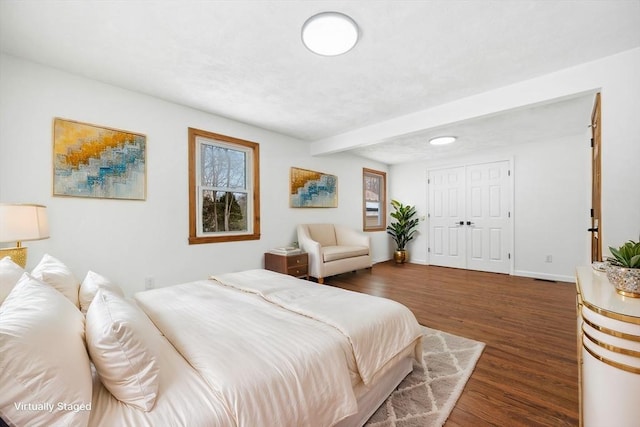 bedroom with dark wood-style flooring, a closet, and baseboards