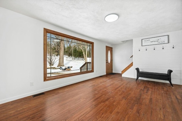 foyer entrance featuring baseboards, a textured ceiling, visible vents, and dark wood-style flooring