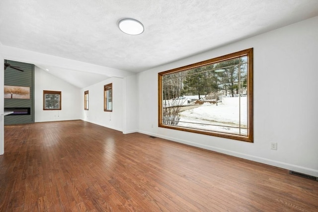 unfurnished living room featuring visible vents, a fireplace, hardwood / wood-style flooring, and baseboards