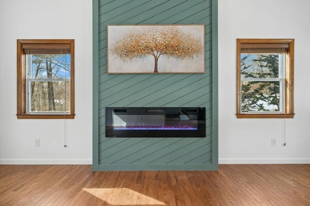 interior details with a glass covered fireplace, baseboards, and wood finished floors