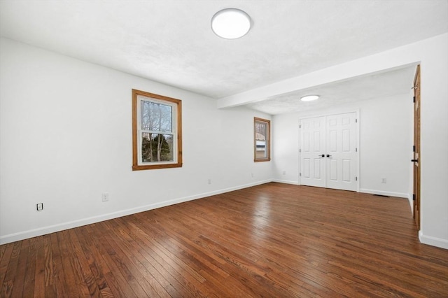 unfurnished room with baseboards and dark wood-style flooring