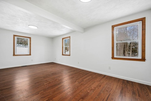 spare room with dark wood-type flooring, beam ceiling, a textured ceiling, and baseboards