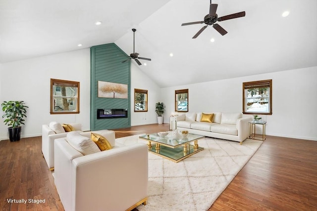 living area featuring a healthy amount of sunlight, a large fireplace, and wood finished floors