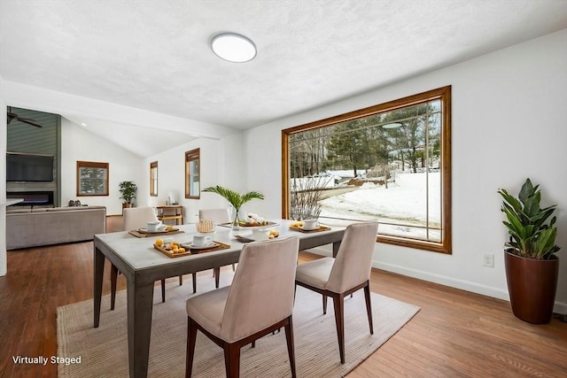 dining area featuring lofted ceiling, wood finished floors, and baseboards