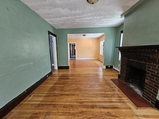 interior space with a baseboard radiator, a brick fireplace, and wood-type flooring