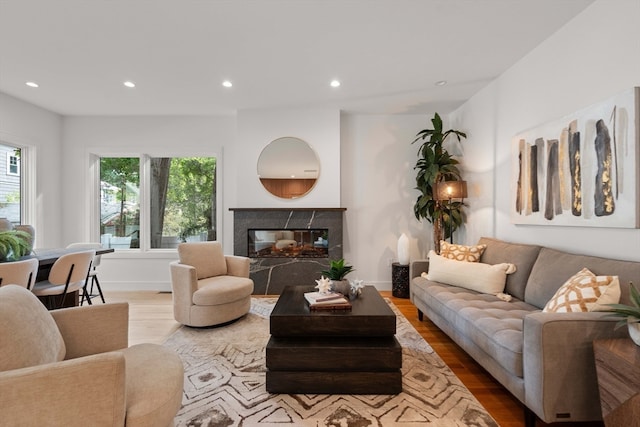 living room featuring a high end fireplace and light hardwood / wood-style flooring