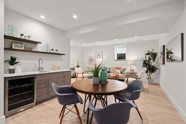 bar featuring wine cooler, light hardwood / wood-style flooring, and sink