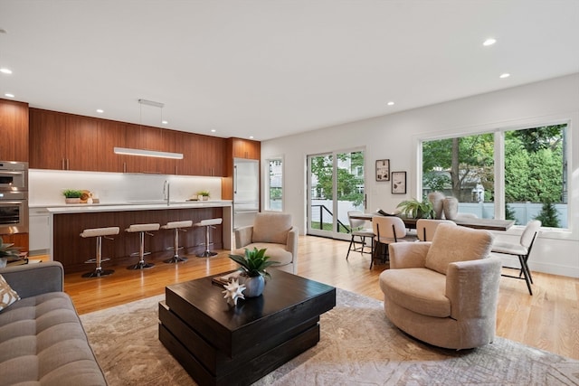 living room with sink, light hardwood / wood-style flooring, and plenty of natural light